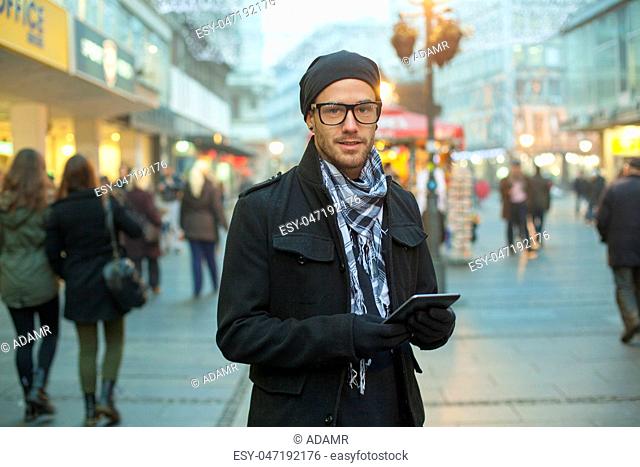 Urban man holdin tablet computer on street