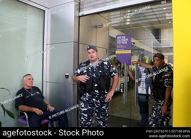 20 July 2023, Lebanon, Beirut: Lebanese policemen secure the entrance of a local bank that two depositors stormed in Beirut demanding to withdraw their trapped...