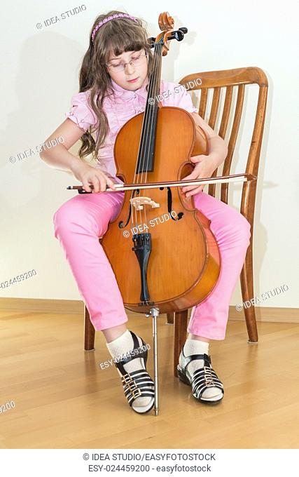Pretty young girl practice playing cello sitting on chair