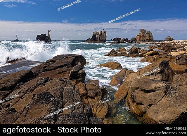 Waves wash around the rocks at Pointe de Pern, in the background the two relay towers of Phare de Nividic, Île d'Ouessant, France, Brittany