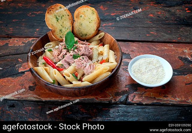 Pasta with tuna, garlic bread and parmesan cheese aside isolated on rustic wooden background