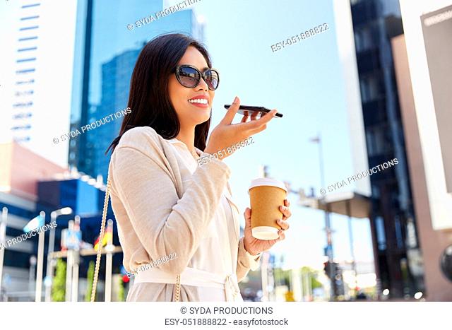 woman recording voice by smartphone in city