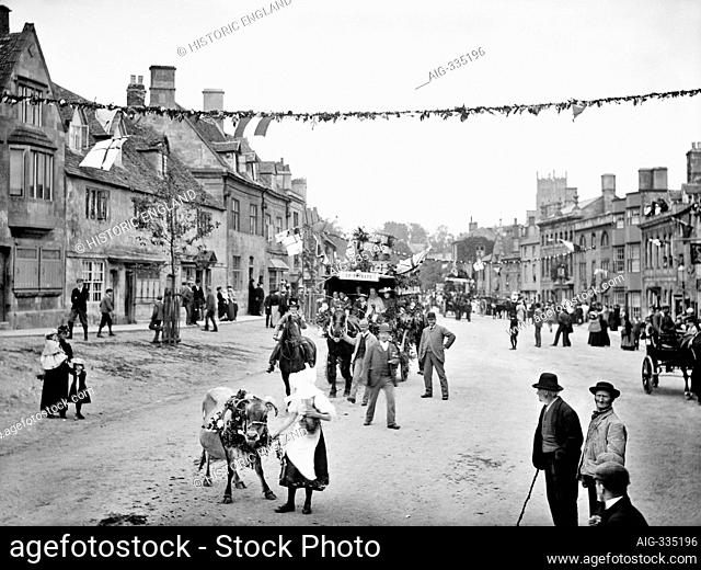CHIPPING CAMPDEN, Gloucestershire. A milkmaid with a calf followed by a cart bedecked in flowers and flags form part of the procession through the Cotswold town...