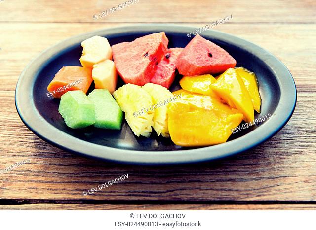 cooking, kitchen and food concept - plate of fresh juicy fruits at asian restaurant or home