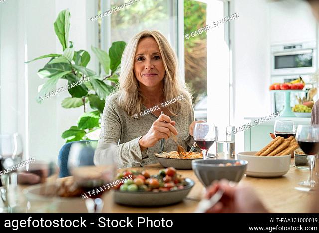 Senior woman looking at the camera while having lunch in dining room