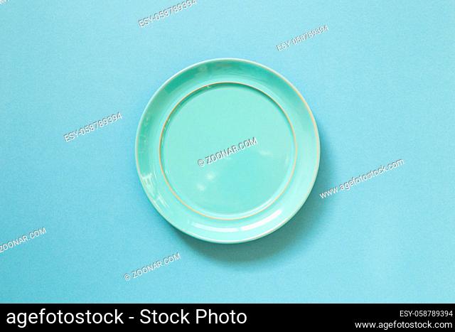 Empty ceramic round plate isolated on blue background. top view