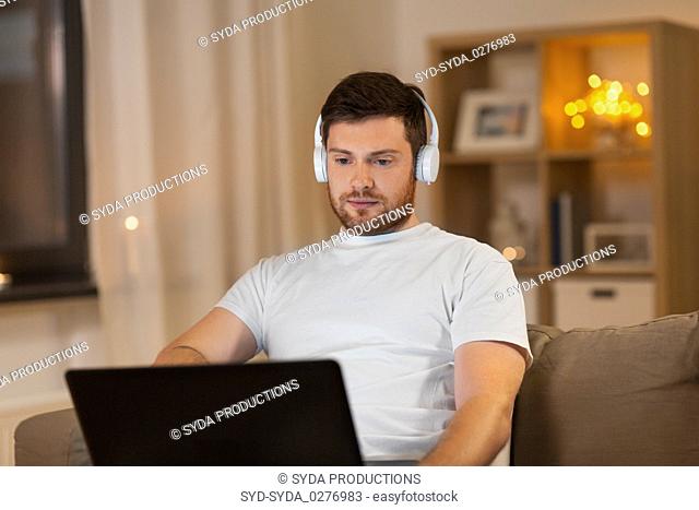 man in headphones with laptop computer at night