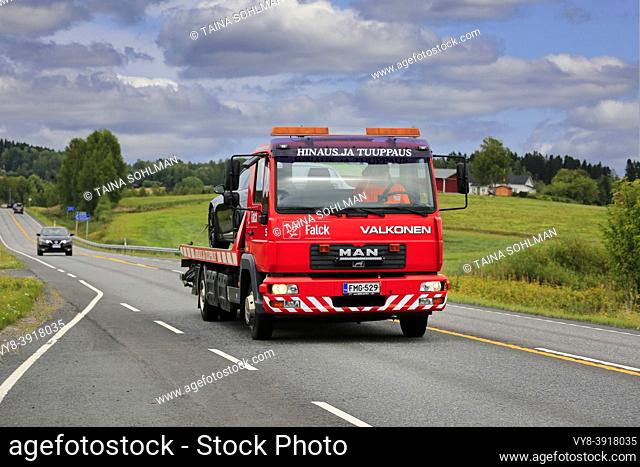 Road landscape with MAN flatbed recovery vehicle of Hinaus ja Tuuppaus Antti Valkonen carrying damaged car. Ikaalinen, Finland. Aug 12, 2018