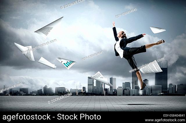 Cheerful jumping businesswoman and papers flying in air