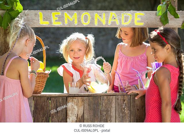 Candid portrait of four girls at lemonade stand in park