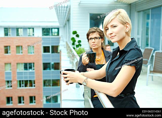 Businesswomen having break on office terrace outdoor drinking coffee