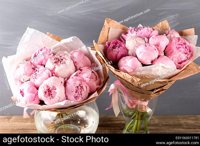Pink peonies in vase on wooden floor and bokeh background - retro styled photo. soft focus