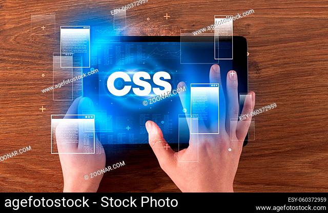 Close-up of a hand holding tablet with CSS abbreviation, modern technology concept