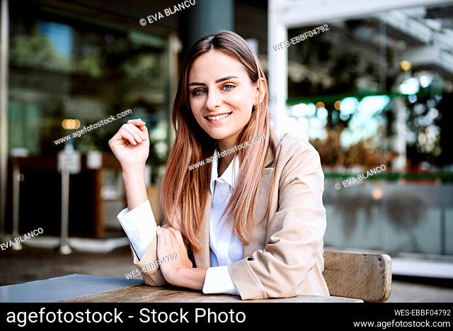 Smiling businesswoman sitting at sidewalk cafe
