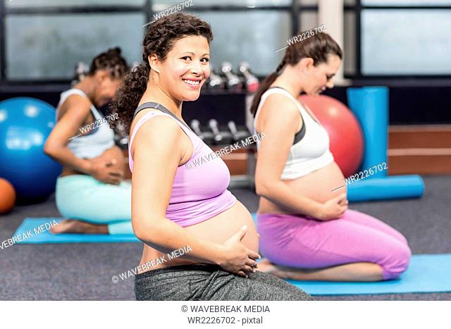 Pregnant women doing exercise on mat
