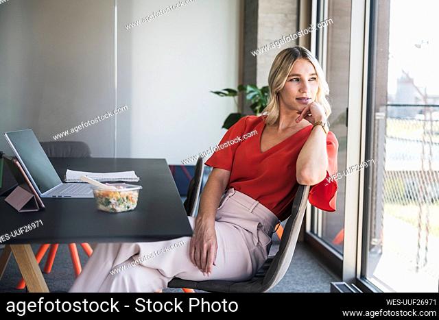 Contemplative businesswoman sitting on chair at desk in office