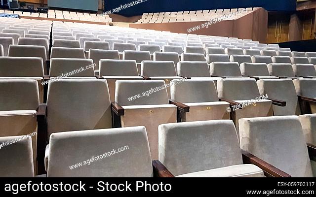 a lot of old beige upholstered chairs without people in the hall for performances and films. Background from many chairs in the stands in a concert hall or...
