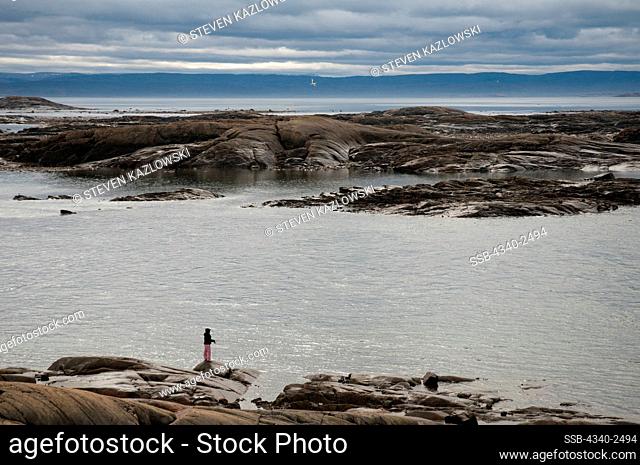 Local woman fishes for arctic char in the Sylvia Grinnell river in summer, Sylvia Grinnell Territorial Park, Baffin Island, Nunavut, Canada