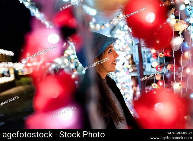 Smiling woman watching a stand on fairground at night