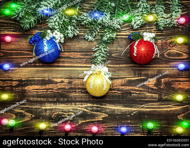 Balls and garland at fir branch on wooden background