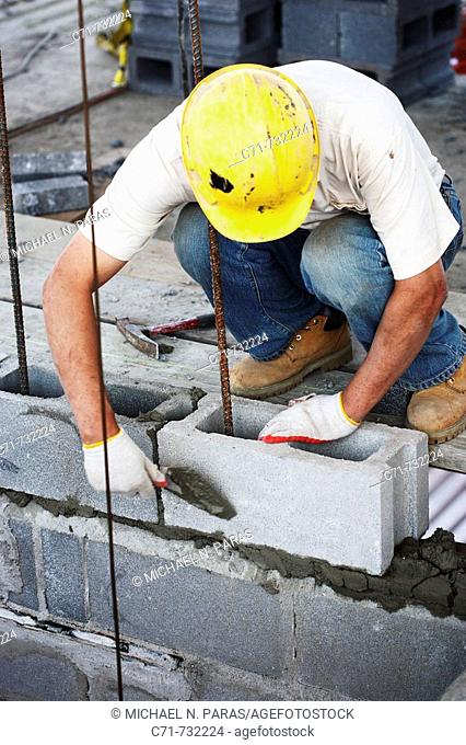 Construction mason laying cement blocks