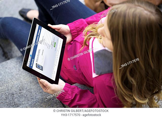 Close up picture of a young woman using Facebook social networking website on an iPad 2