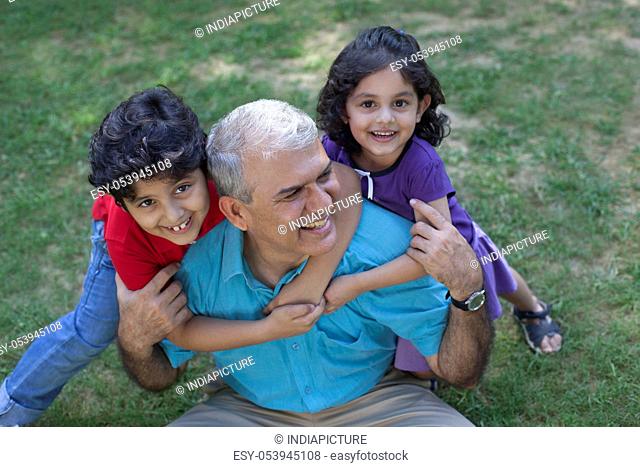 Portrait of grandchildren hugging grandfather