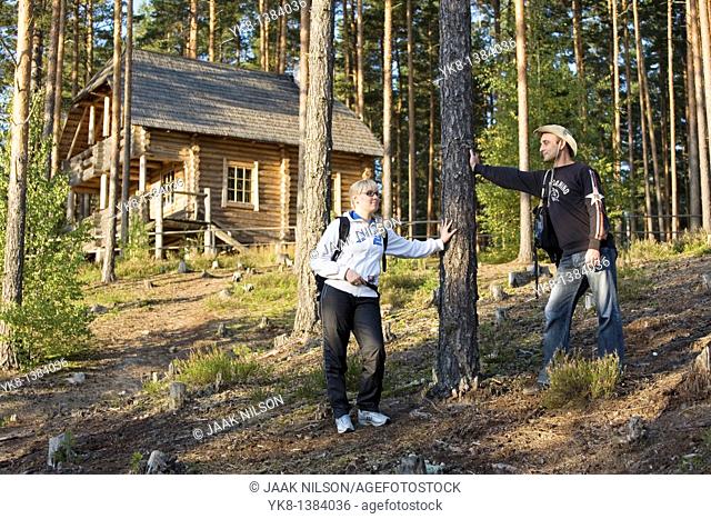 Young Hiking Couple Standing in Forest by Blockhouse in Meenikunno Landscape Reserve, Estonia