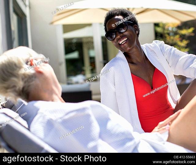 Happy senior women friends sunbathing on spa patio