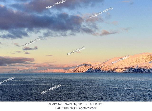 Winterly white coast from the island Sørøya illuminated in colourful light from the setting sun, 9 March 2017 | usage worldwide