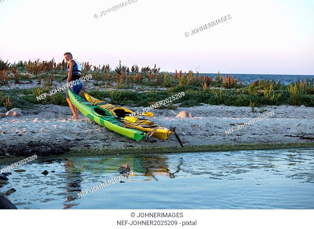 Mature man pulling kayaks