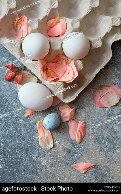 paper tray with eggs and dried petals on a stone background