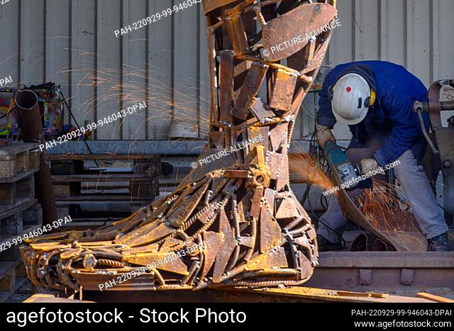 29 September 2022, Saxony-Anhalt, Magdeburg: The scrap artist Pawel Lickas is cutting parts for a sculpture on the grounds of the Rothensee waste-to-energy...
