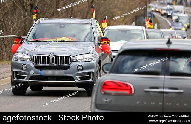 06 March 2021, Saxony, Leipzig: With Germany flags on their cars, critics of the Corona measures drive through the city in a motorcade