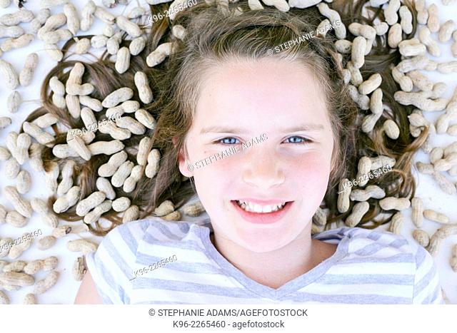 young girl looking at camera surrounded by peanuts
