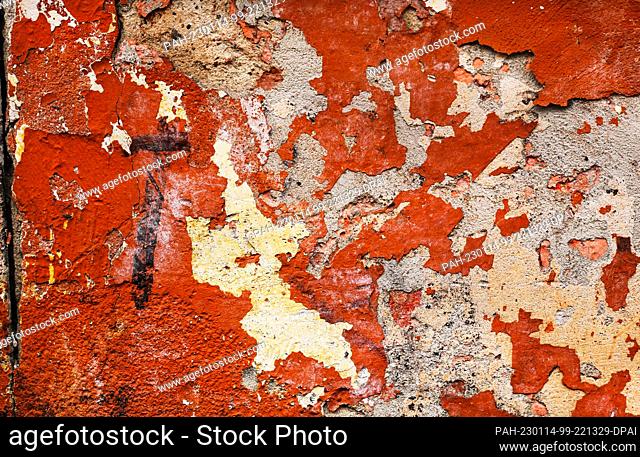 08 January 2023, Berlin: 08.01.2023, Berlin. Remnants of chipped plaster and paint from old graffiti form colorful, random structures and patterns on a wall on...