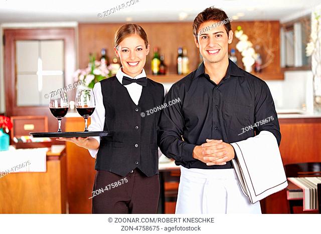 Portrait von einem Kellner und einer Kellnerin mit Wein im Restaurant