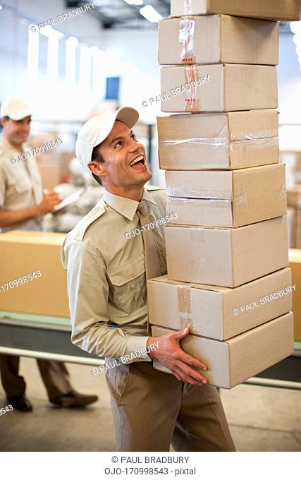 Worker carrying stack of boxes in shipping area
