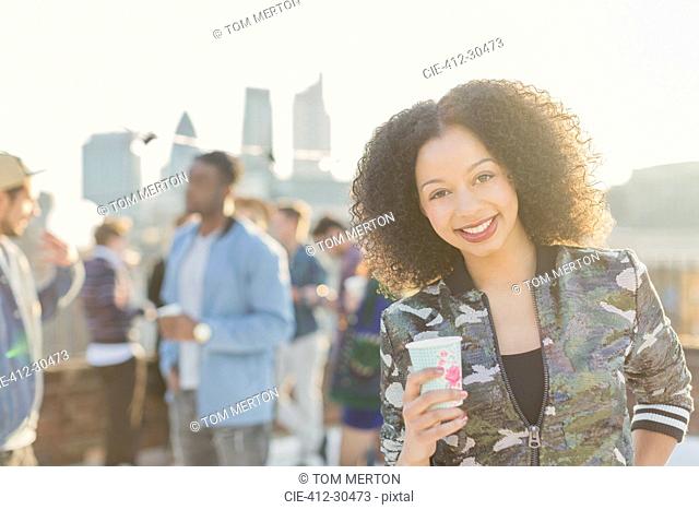 Portrait smiling young woman drinking cocktail at rooftop party