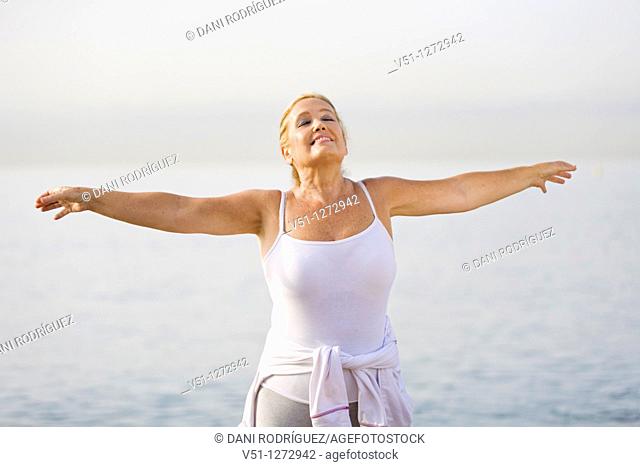 Portrait of a senior adult woman stretching at the beach