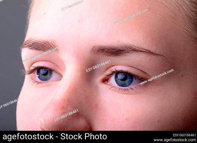 Close up of blue eyes of caucasian businesswoman isolated on grey background