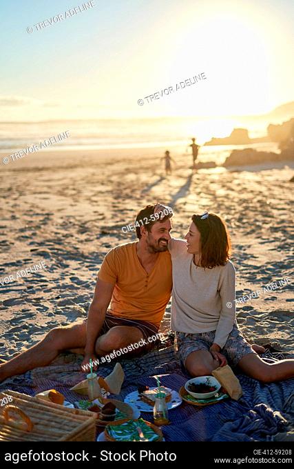 Happy affectionate couple enjoying picnic on sunny beach