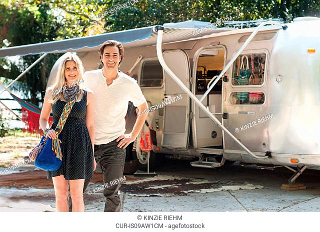 Portrait of couple standing in front of converted boutique airstream trailer