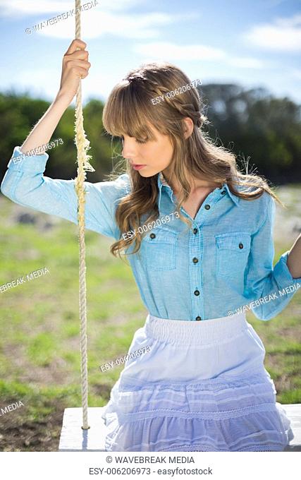 Pretty young model relaxing sitting on swing