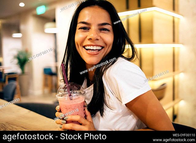 Black-haired woman drinking a smoothie in cafe
