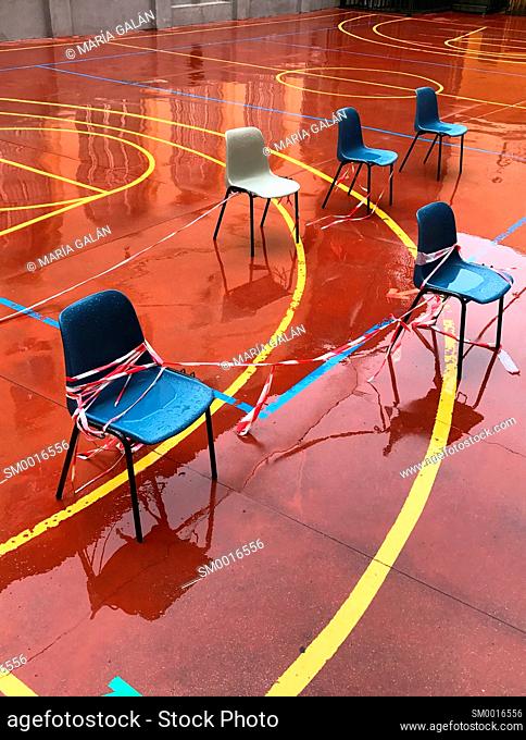 Empty chairs in playground with wet pavement