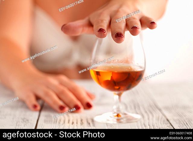 Female hand rejecting glass with alcoholic beverage