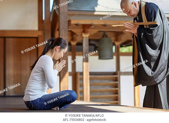 Japanese priest preaching to woman at a temple