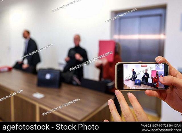 27 October 2023, North Rhine-Westphalia, Gelsenkirchen: A woman films one of the accused daycare workers and her lawyer with her smartphone
