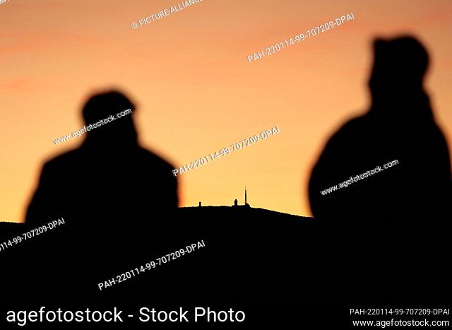 13 January 2022, Saxony-Anhalt, Wernigerode: The evening sun bathes the horizon of the Harz Mountains in a warm light. A visitor castle terrace watching the...